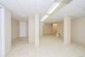 Spacious room featuring light-toned tile flooring, neutral wall paint, and a drop ceiling with integrated lighting