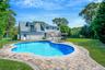 View of pool with a patio area and view of scattered trees