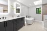 Bathroom with a soaking tub, a skylight, double vanity, tiled shower, and a sink