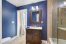 Jack and jill, bathroom hardwood vanity with a light-colored countertop, framed mirror, and a two-light fixture