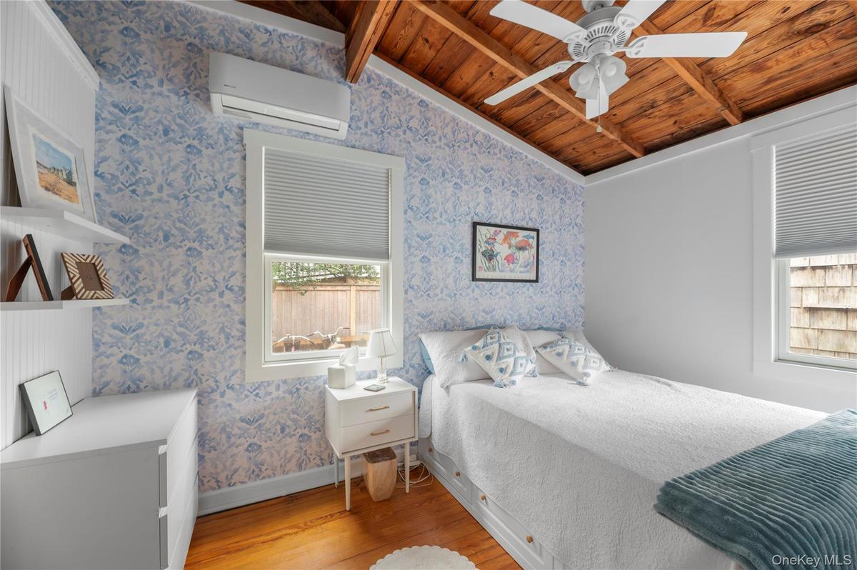 Bedroom with light wood-type flooring, wallpapered walls, wooden ceiling, a wall unit AC, and ceiling fan