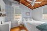 Bedroom with light wood-type flooring, wallpapered walls, wooden ceiling, a wall unit AC, and ceiling fan