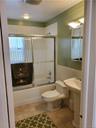 Bathroom featuring visible vents, tile walls, tile patterned floors, toilet, and enclosed tub / shower combo