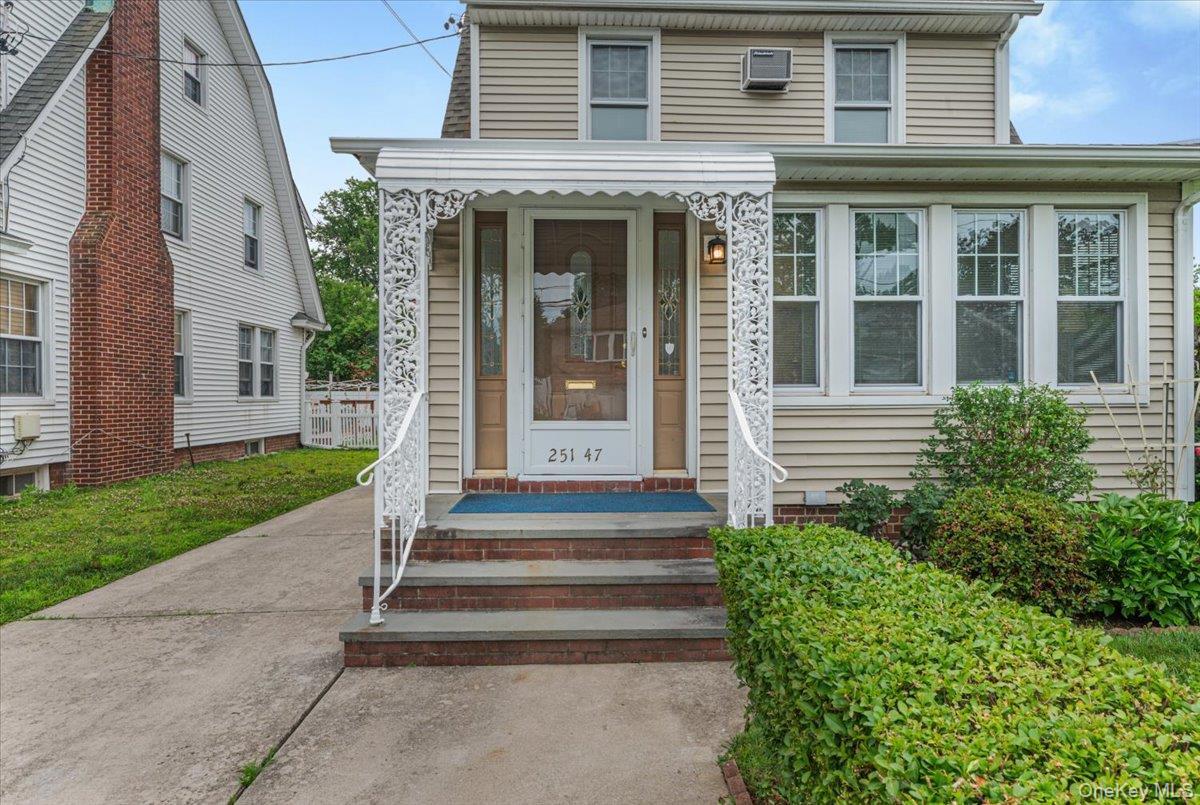 Siding exterior featuring a prominent front entrance with an ornamental metal awning and handrail