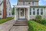 Siding exterior featuring a prominent front entrance with an ornamental metal awning and handrail