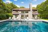 Back of property featuring a balcony, a patio, an outdoor pool, and a chimney