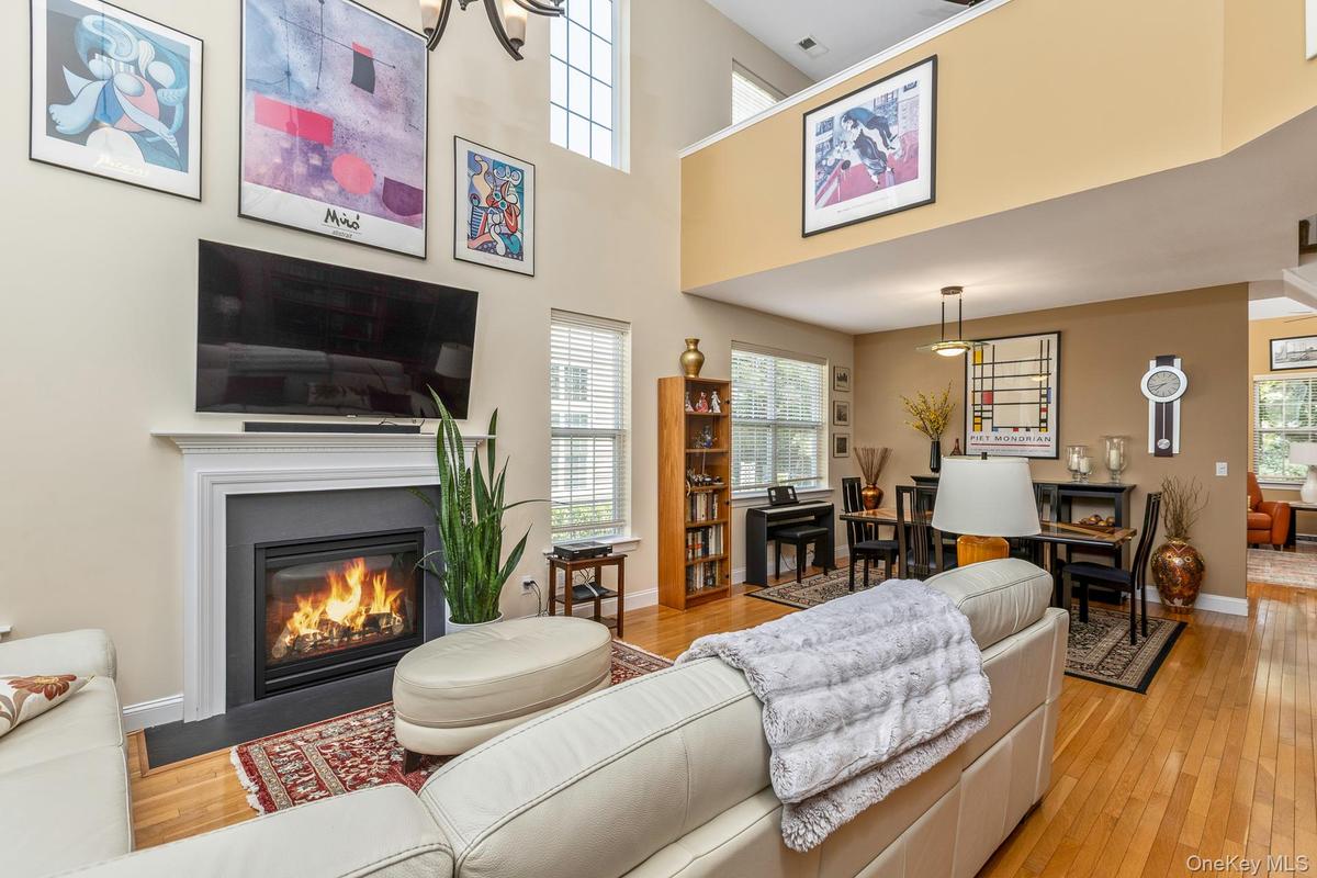 Open-concept living space featuring a fireplace, a dining area, and a lofted upper level with an overlook