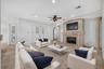 Virtually Staged. Family Room showcases a gas fireplace and French doors opening to the covered lanai and pool area