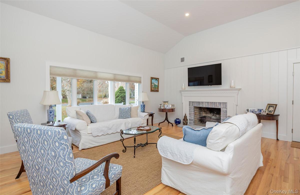 Living area featuring light wood-type flooring, vaulted ceiling, a brick fireplace, and recessed lighting