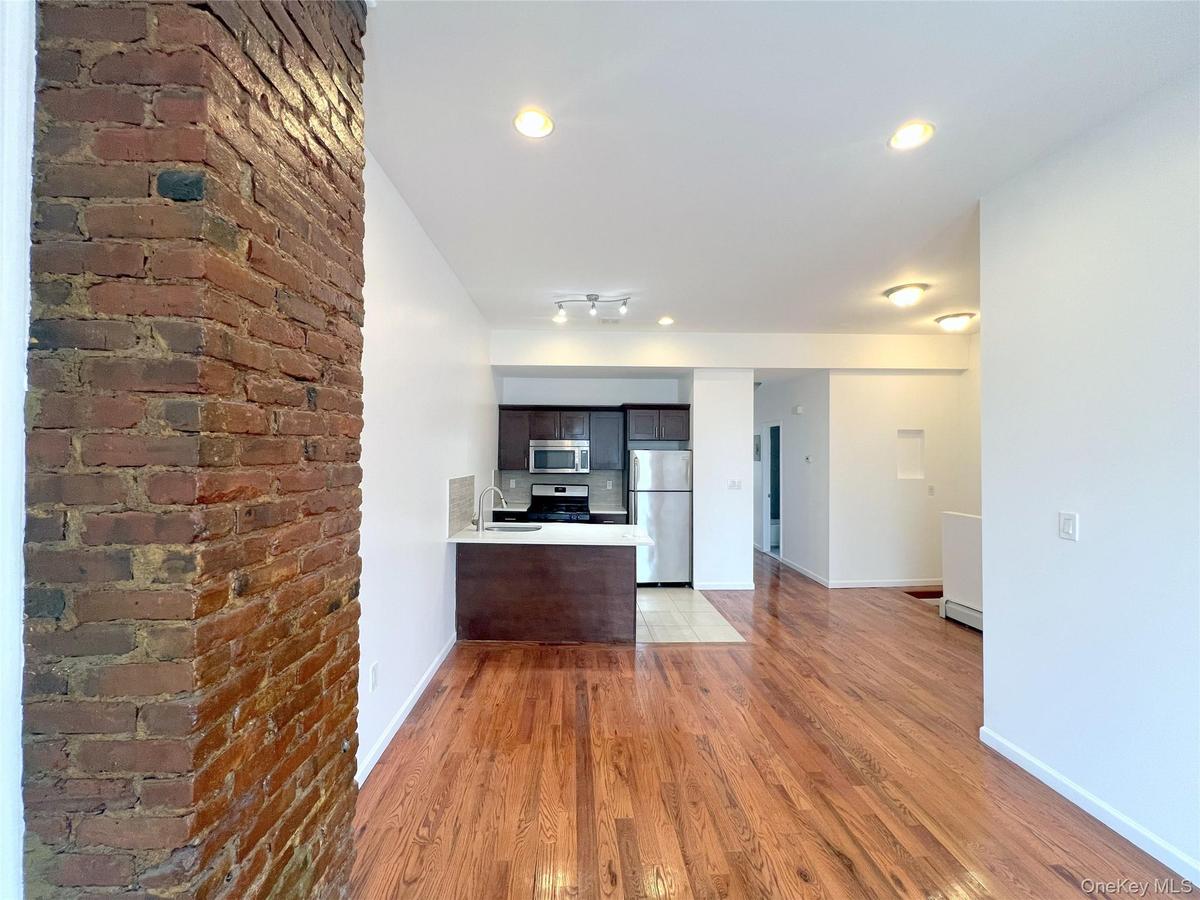 Kitchen with appliances with stainless steel finishes, light wood-type flooring, light countertops, a peninsula, and open floor plan
