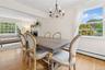 Dining space with a brick fireplace, a chandelier, light wood-type flooring, beamed ceiling, and baseboard heating