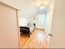 Bedroom featuring lofted ceiling, baseboard heating, and light wood-type flooring