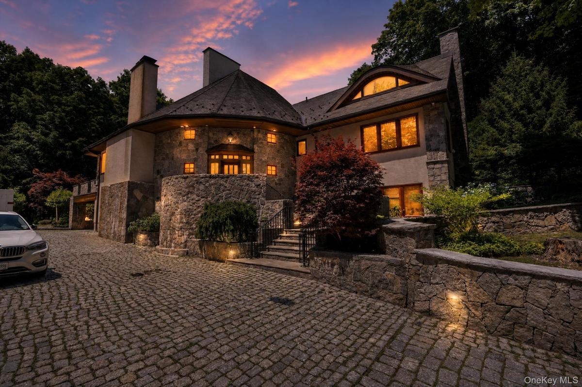 Stone and stucco exterior featuring multiple chimneys and a distinctive rounded facade