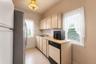 Kitchen featuring tile flooring, a stainless steel refrigerator, neutral cabinetry, a built-in dishwasher, and a window with natural light