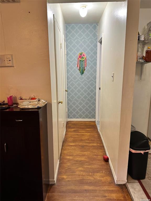 Corridor featuring wallpapered walls, an accent wall, baseboards, and light wood finished floors