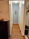 Corridor featuring wallpapered walls, an accent wall, baseboards, and light wood finished floors