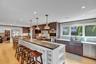 Kitchen with light wood-type flooring, hanging light fixtures, a kitchen breakfast bar, appliances with stainless steel finishes, and ornamental moldi