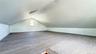 Expansive attic space featuring wood-finish flooring, a window, recessed lighting, and a sloped ceiling