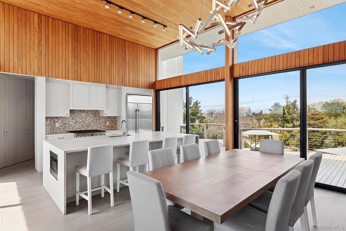 Dining space featuring rail lighting, a wealth of natural light, a towering ceiling, and a notable chandelier