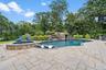Outdoor pool featuring a patio area, an in-ground hot tub, and view of wooded area