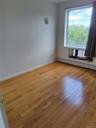 Empty room with baseboard heating and light wood-style floors