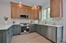 Kitchen featuring stainless steel appliances, light stone countertops, light wood finished floors, backsplash, and ornamental molding