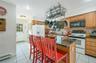 Kitchen featuring white appliances, light tile patterned floors, a center island, backsplash, and baseboard heating