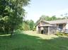 Side view of the four-bedroom unit featuring a screened enclosure, a wood deck, a brick chimney, and vinyl siding