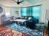 Living area featuring wood finished floors, ceiling fan, an AC wall unit, baseboards, and beam ceiling