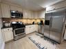 Kitchen featuring stainless steel appliances, cream cabinets, dark stone counters, and decorative backsplash