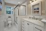 Bathroom featuring wainscoting, light tile patterned floors, vanity, and enclosed tub / shower combo