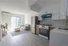 Kitchen with appliances with stainless steel finishes, under cabinet range hood, backsplash, light wood-style flooring, and white cabinetry