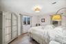 Bedroom featuring wood finished floors, crown molding, and a wainscoted wall