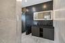 Contemporary bathroom featuring a double vanity with integrated sinks and dark cabinetry, illuminated by a large backlit mirror