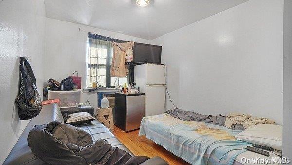 Bedroom with white fridge and wood finished floors