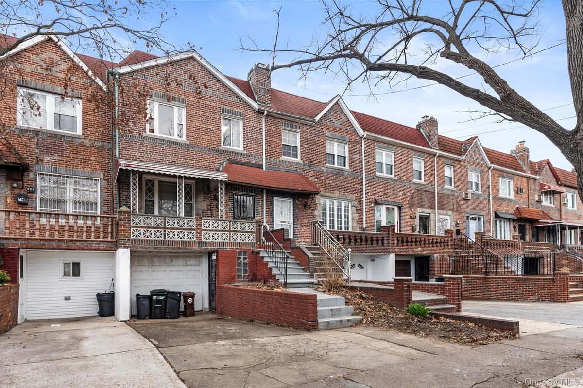 Townhome / multi-family property with brick siding, a garage, a chimney, concrete driveway, and stairway