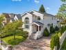 Elegant brick Colonial with a two-story arched entry portico, white railing details, and a circular brick driveway