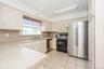 Kitchen featuring light-toned cabinetry with brass hardware, a stainless steel side-by-side refrigerator, a black electric range, and a stainless stee