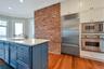 Kitchen featuring ornamental molding, brick wall, blue cabinets, sink, and built in appliances