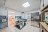 Kitchen with stainless steel fridge, wainscoting, tile walls, and brown cabinetry