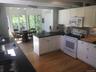 Kitchen with white appliances, a peninsula, light wood-type flooring, a sink, and dark countertops
