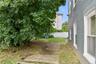 Side yard featuring a mature tree, concrete patio sections, and a privacy fence