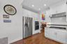 Kitchen featuring backsplash, stainless steel appliances, white cabinets, under cabinet range hood, and dark wood finished floors