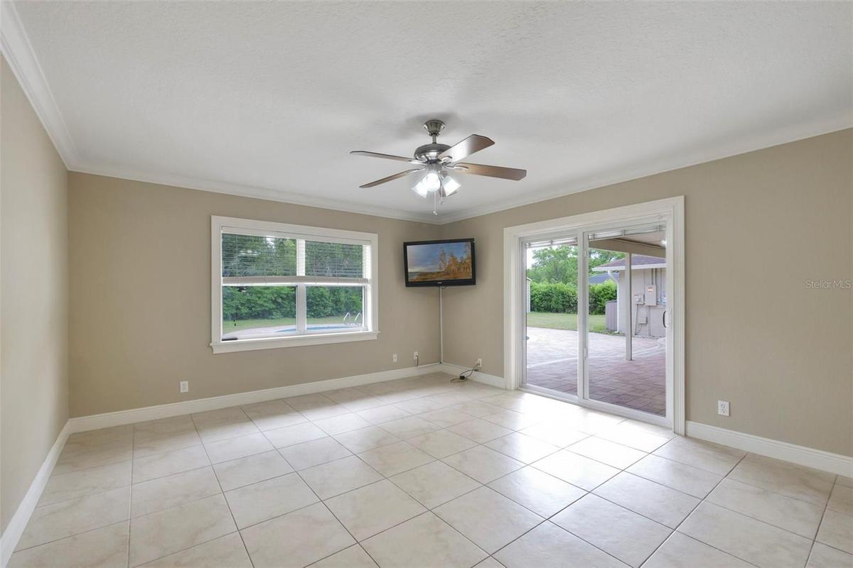 A VERSATILE BONUS SPACE is ideal as a media room, game room, or second living area, with sliding glass doors opening to the patio and pool for seamles