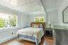 Bedroom featuring dark wood-style flooring, beamed ceiling, and wooden walls