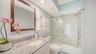 Guest bathroom with granite countertop and glassed shower/tub combination.