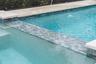 Custom tile and travertine flooring surround the saltwater pool.