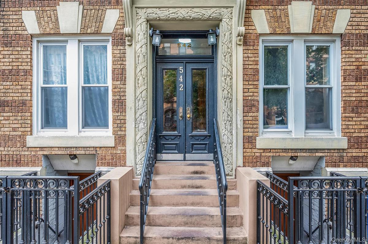 Entrance to property featuring brick siding, a gate, and french doors