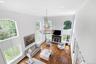 Two-story living area featuring hardwood flooring, a central chandelier, and a fireplace with a stone surround