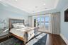 Bedroom with access to exterior, dark wood finished floors, ornamental molding, recessed lighting, and lofted ceiling